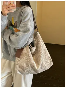 Vista laterale di una modella con tote bag jacquard beige e spallacci in pelle marrone, al chiuso