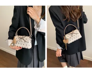 Due viste della borsa beige a pois neri, con fiocco e ciondolo a cuore, indossata su un blazer nero
