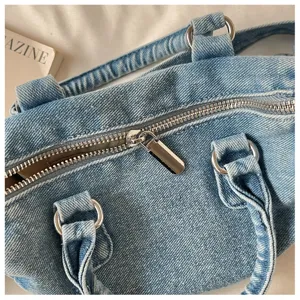 Gros plan sur le denim bleu clair délavé, la fermeture éclair argentée et les anneaux métalliques
