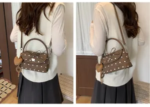 Vista posteriore e laterale: borsa marrone a pois bianchi, con fiocco e ciondolo a cuore, indossata.