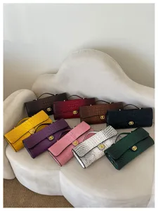 Negen clutches met krokodillenprint in diverse kleuren, gerangschikt op een crèmekleurige fauteuil