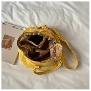 Détail du sac jaune ouvert, avec doublure beige, fermeture éclair, poignées et bandoulière
