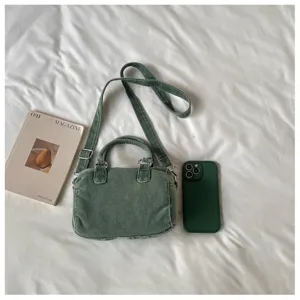 Vue à plat du tissu vert délavé, des coutures, des poignées et de la bandoulière réglable