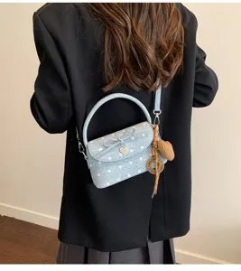 Vista da dietro di una mini borsa azzurra a pois, con fiocco e ciondoli a cuore, su un cappotto nero