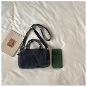 Vue à plat d’un sac en denim gris foncé délavé, avec poignées, bandoulière et clips métalliques