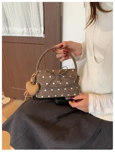 Modella con borsa marrone a pois bianchi, patta a fiocco e ciondolo a cuore in maglia