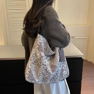 Borsa tote capiente in tessuto stampato grigio-marrone, con manici in pelle, portata a spalla