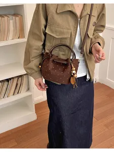 Sac seau marron à pois, en suédine, avec anses en cuir et pompon de perles, porté en bandoulière