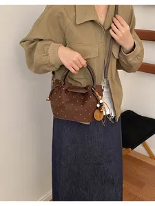 Modèle portant un sac brun à pois, orné de breloques en bois et d'une bandoulière amovible