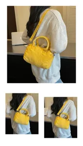 Vue portée d’un sac jaune délavé, arrondi, avec de courtes anses et une bandoulière réglable