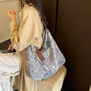 Capiente borsa tote a stampa blu e bianca, con tracolla in ecopelle marrone, indossata a spalla