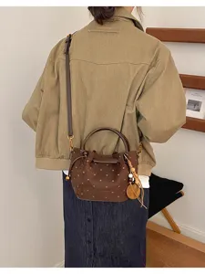 Vue de dos du sac brun à pois façon daim, porté en bandoulière avec breloque en bois et pompon perlé