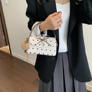 Piccola borsa a pois color avorio, con fiocco, ciondolo a cuore e sottile tracolla marrone