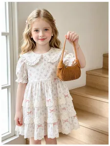 Close view of a child holding a brown mini handbag with a curved shape and long decorative tassels