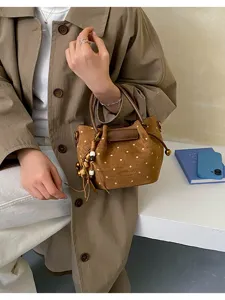 Vue portée d’un sac brun à pois, avec des breloques en perles de bois et des anses courtes