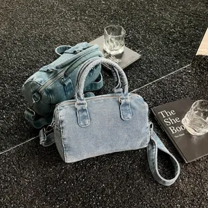 Sac Boston en denim bleu délavé, avec poignées, bandoulière et zip métallique, vu sous deux angles