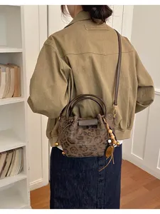 Vue de dos d’un modèle portant un sac seau brun léopard avec perles en bois et pendentifs en cuir