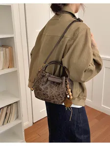 Vue de dos d’un modèle portant un sac léopard avec bandoulière foncée et breloque en perles de bois