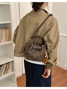 Vue de dos d’une femme portant un sac brun à imprimé léopard, orné de perles en bois, en intérieur