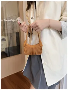 A small brown suede-look bag with dense fringe, shown hanging from its short handle