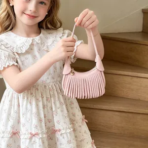 Pink suede-look mini handbag with long fringe and a single handle, held by a young girl.