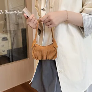 Brown faux suede mini fringe handbag with a zip top, held by a model in a lifestyle scene