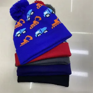 Stacked knitted hats with a blue pom-pom beanie featuring playful construction vehicle motifs