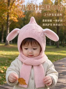 Child wearing a pink knitted hood and scarf with bunny ears, photographed in an autumn park