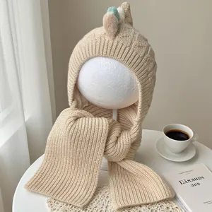 Beige rib-knit hood and scarf displayed on a mannequin, with small dinosaur-style horns