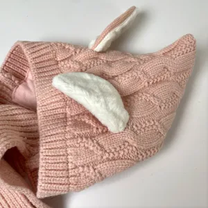 Close-up of pink cable-knit texture with soft white plush bunny-ear accents on the fabric
