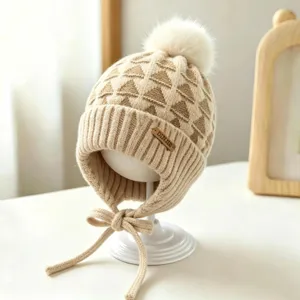 Close-up of a cream and camel knit hat with geometric jacquard, ribbed brim, pom-pom and ties