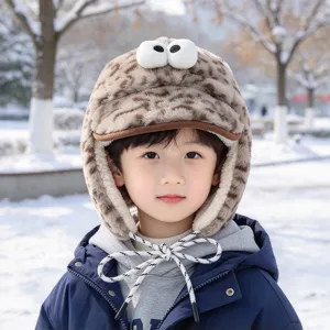 Enfant avec bonnet peluche léopard, yeux en relief et rabats d’oreilles dans un parc enneigé