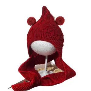 Red knitted winter hat for children with pointed top, two pom-poms and an attached scarf