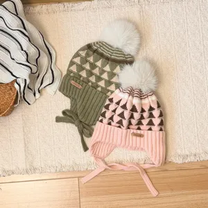 Two children's knit hats in green and pink, with geometric patterns, earflaps and fluffy pom-poms