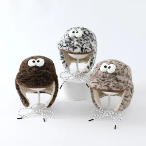 Trois bonnets doux à rabats, imprimés léopard, bruns, noirs et gris, avec yeux décoratifs et liens