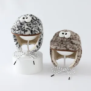 Deux bonnets pelucheux à motif léopard, yeux fantaisie et liens, présentés sur des supports blancs