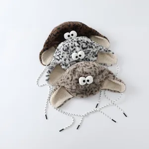 Trois bonnets en peluche à motif léopard, yeux fantaisie et liens tressés, sur fond blanc