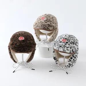 Trois bonnets léopard en fausse fourrure, en brun, beige et noir et blanc, sur supports blancs