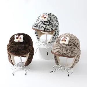 Trois bonnets en fausse fourrure léopard avec motif de lion, présentés sur des supports blancs