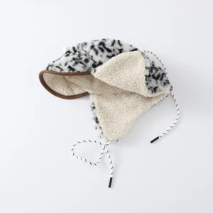 Détail d’un bonnet d’hiver léopard noir et blanc, doublé de sherpa crème avec cordons à nouer