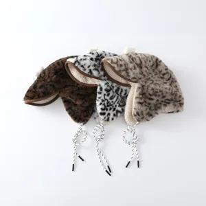 Trois bonnets léopard en fausse fourrure, en brun, noir et blanc, et beige, avec pompons et liens