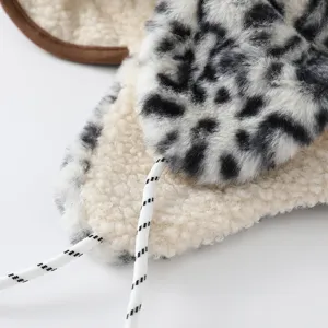 Gros plan sur la peluche léopard noir et blanc, la doublure sherpa crème et le cordon rayé