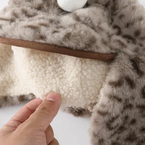 Gros plan sur le tissu peluche à imprimé léopard, le panneau écru effet mouton et le bord brun