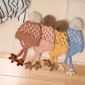 Four children's knit hats in caramel, pink, yellow and blue, with pom-poms and earflap ties