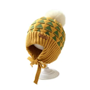 Yellow-green baby knit hat with geometric pattern, earflaps, chin ties and white pom-pom