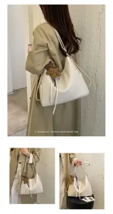 Lifestyle view of a cream shoulder bag with bear charm, showing its handles and soft silhouette