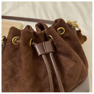 Close-up of brown suede bag with diamond stitching, leather drawcord trim and antique-gold eyelets