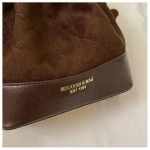 Close-up of brown suede-like diamond stitching and dark base with gold lettering