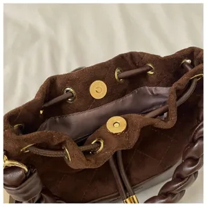 Close-up of brown suede bag opening with dark lining, gold eyelets and magnetic snap clasp