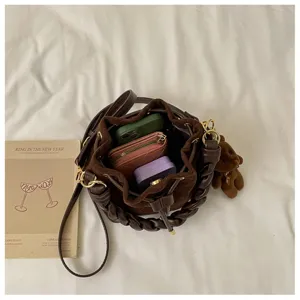 Overhead view inside the brown bucket bag, showing a suede pouch, everyday items and bear charm